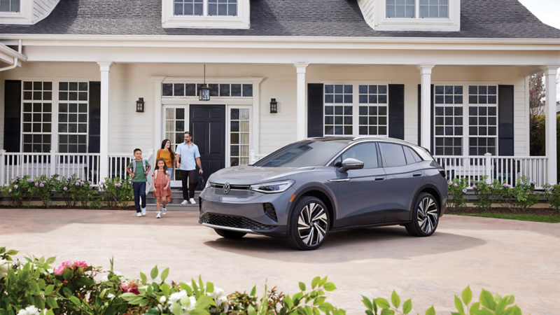 A family approaches a VW ID.4 parked in the driveway.