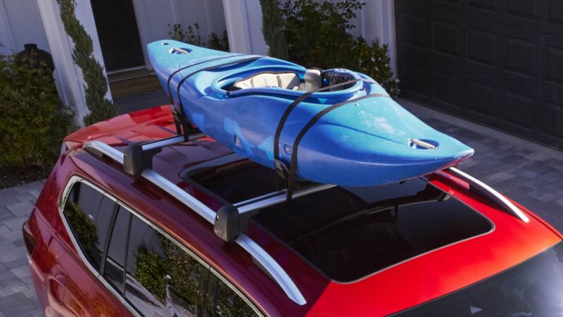 Blue kayak on top of a red SUV