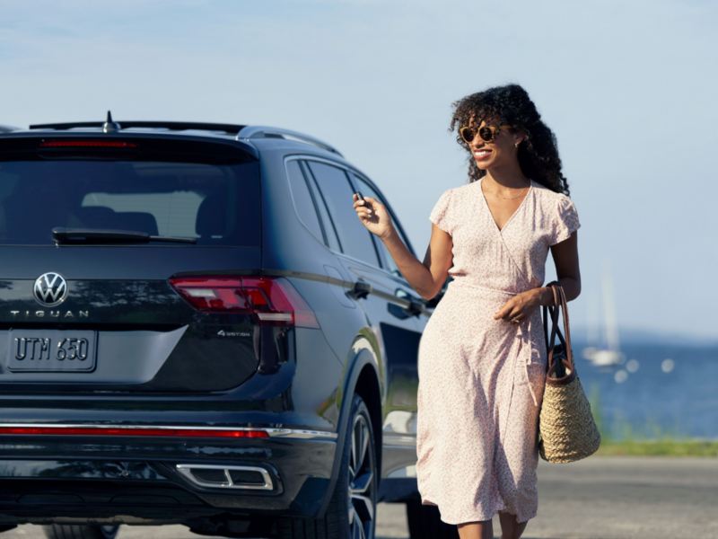 Une femme portant une robe d'été s'éloignant d'un véhicule tout en tenant les clés à la main