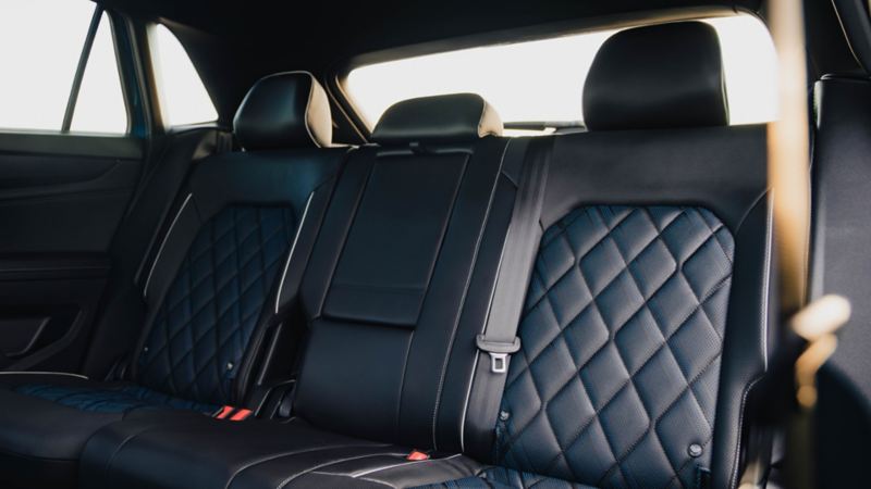 Black leather back seats of a car with diamond-stitched pattern