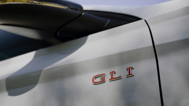 Close-up of the front badge on a Volkswagen Jetta GLI 2025, with the letters "GLI' in red against a chrome background.
