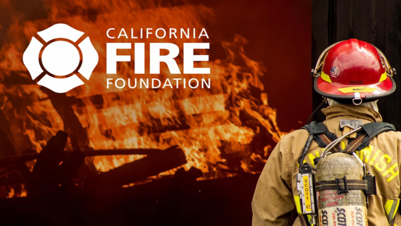 Back view of a fireman standing in front of a fire with the California Fire Foundation logo applied on top of the image