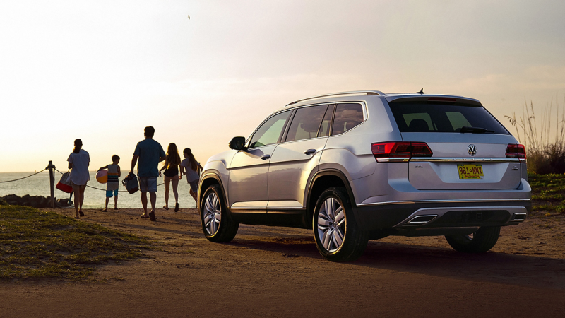 Volkswagen Atlas parked facing the beach with a group of people walking toward the beach. 