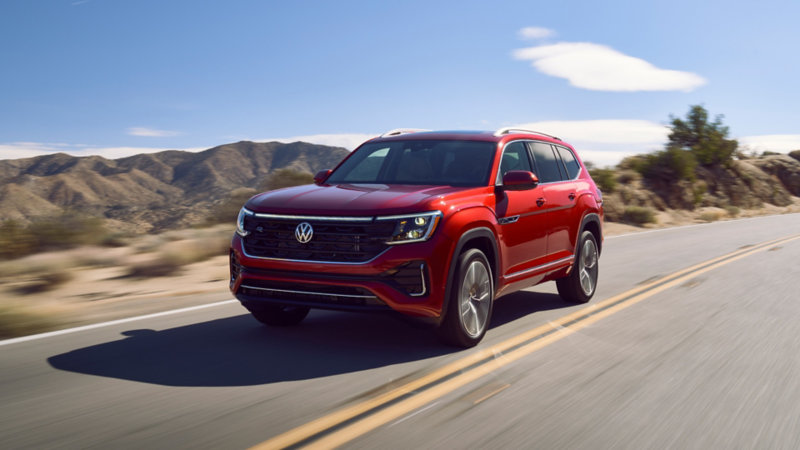 Atlas shown in Aurora Red Metallic seen from the front as it drives on a wooded mountain road.