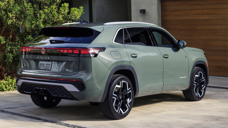 Rear view of an Atlas Cross Sport shown in Dark Sage Metallic parked in the driveway of an upscale house.