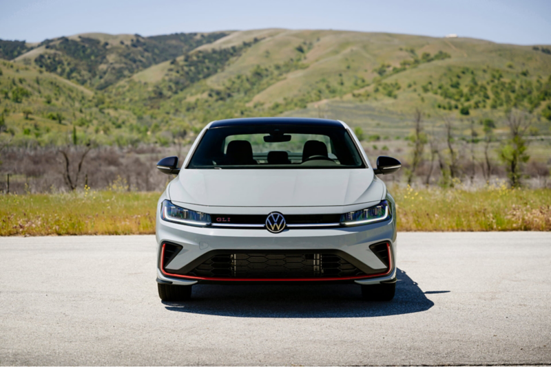 Head-on view of a Jetta GLI shown in Monument Gray parked with wooded hills in the background.