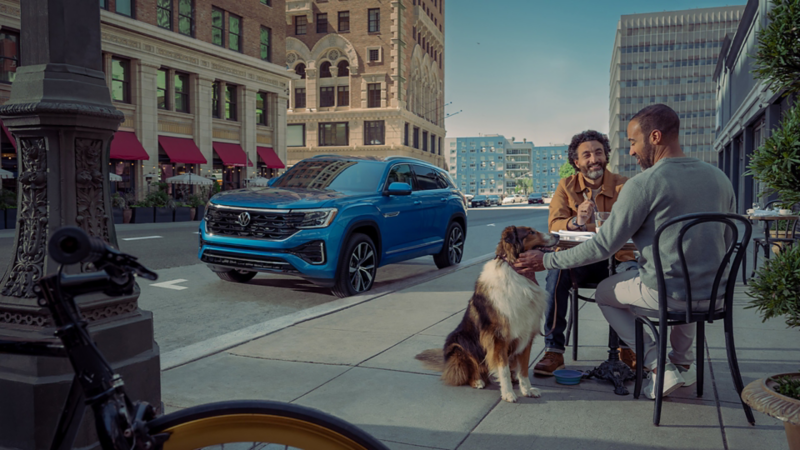 Front ¾ view of the Atlas Cross Sport in Kingfisher Blue Metallic parked on the side of a street with the city in the background.