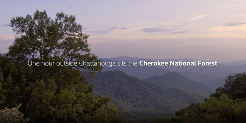 A lavender blue sky with forested mountains and copy that reads One hour outside Chattanooga sits  the Cherokee National Forest.