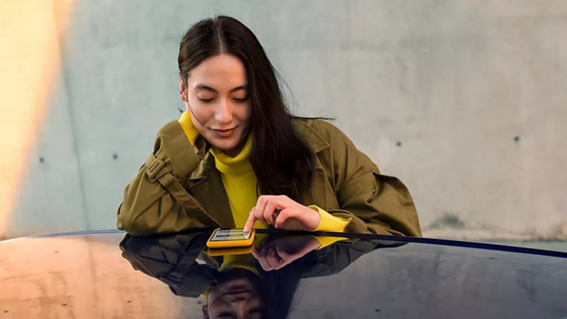 A woman sits at a table casually, scrolling through her phone.