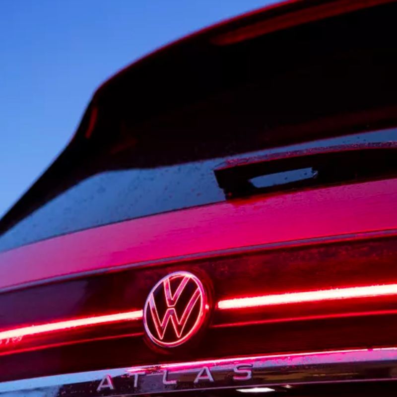Zoomed in rear view of a VW Atlas in Kings Red Metallic that showcases the streamlined LED light and VW logo at dusk.