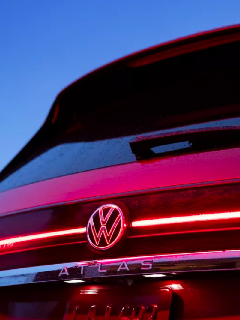 Zoomed in rear view of a VW Atlas in Kings Red Metallic that showcases the streamlined LED light and VW logo at dusk.