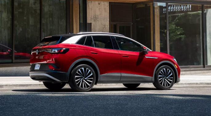 a 2024 ID.4 in Aurora Red Metallic is parked in front of a modern office building on the street.