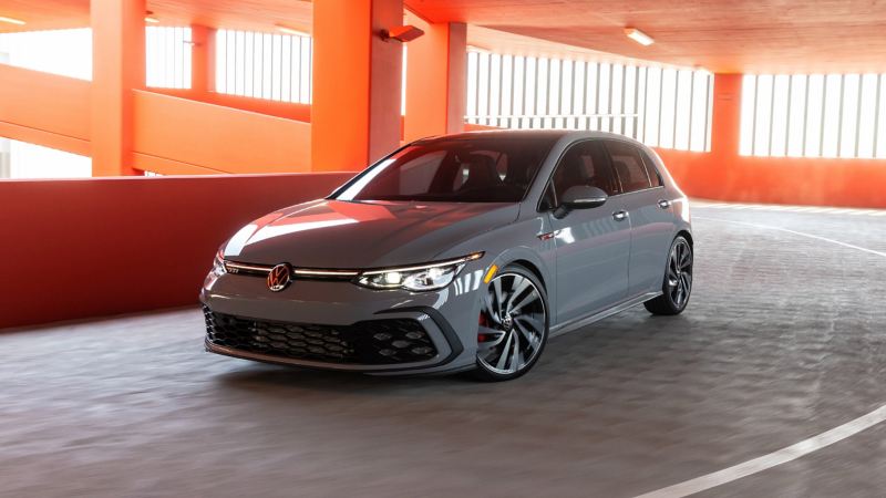 VW Golf GTI in Moonstone Gray parked in garage with clay-colored concrete walls and slopes.