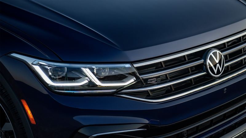 Zoomed in front grill and R badge of a Volkswagen Tiguan in Deep Black Pearl.