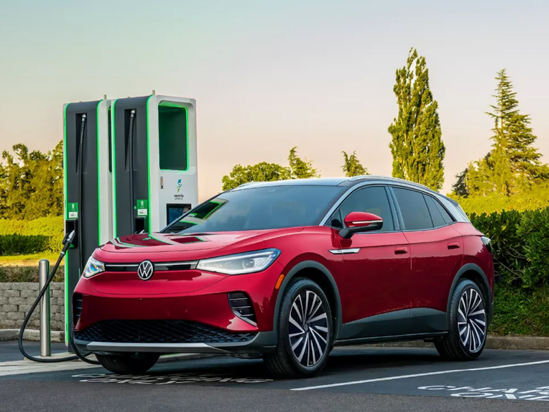 An ID.4 shown in Aurora Red Metallic parked at a charging station.