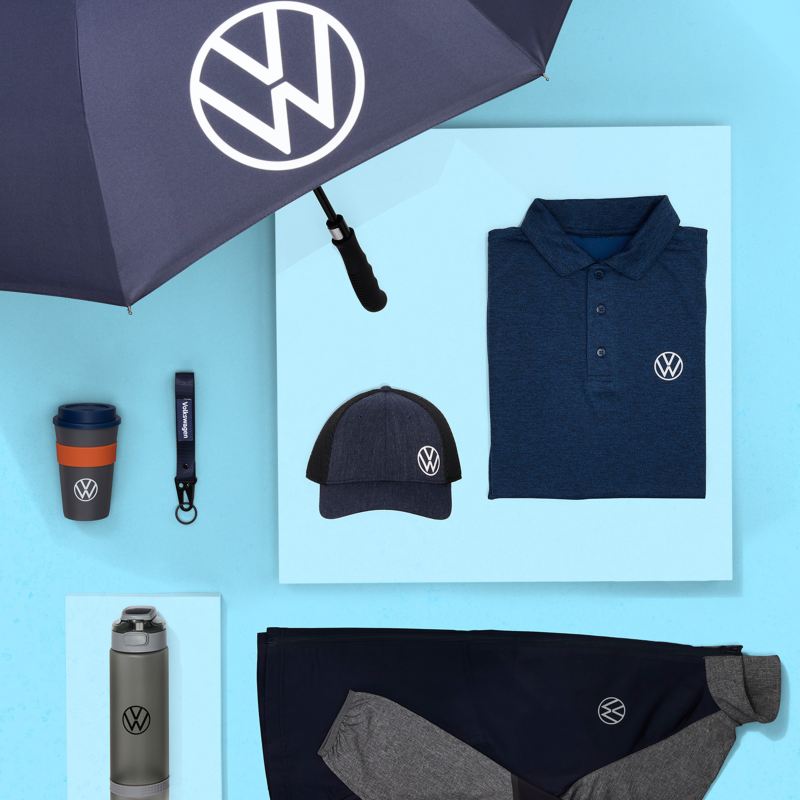 Paraguas de la marca VW, gorra de béisbol, camisa abotonada, chaqueta, botella de agua, taza de viaje y llavero sobre fondo aguamarina.