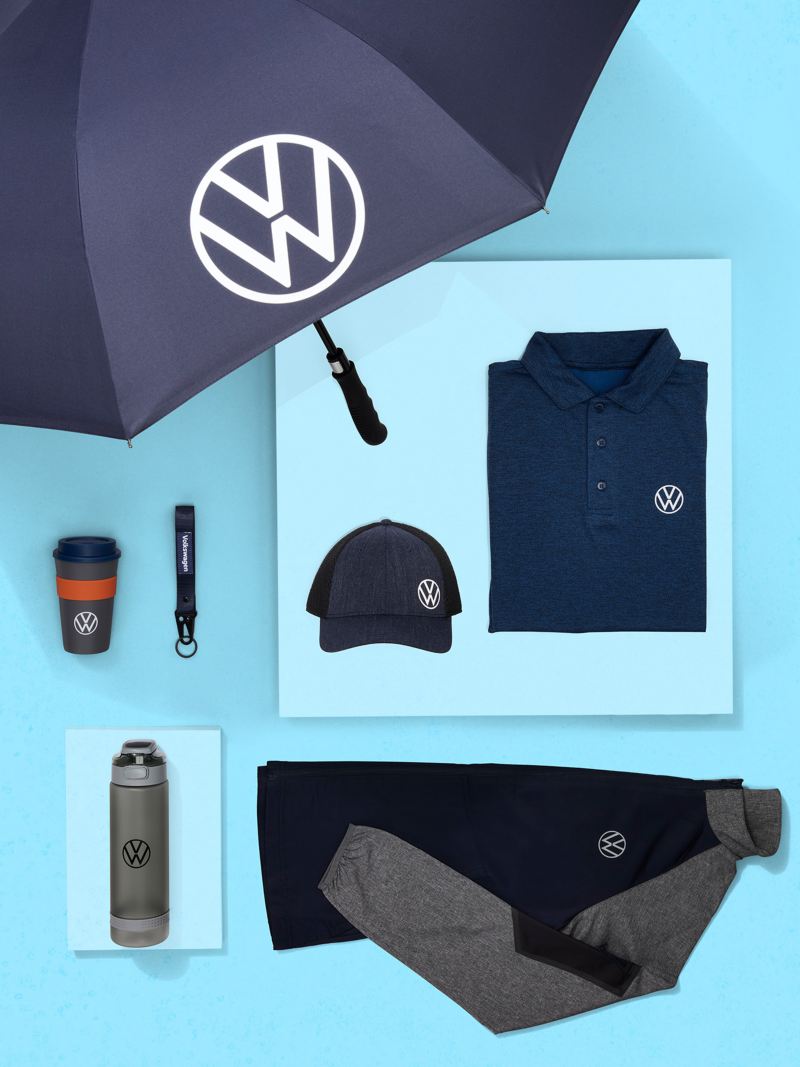 VW branded umbrella, baseball hat, button down shirt, jacket, water bottle, travel mug and keychain on an aqua background.