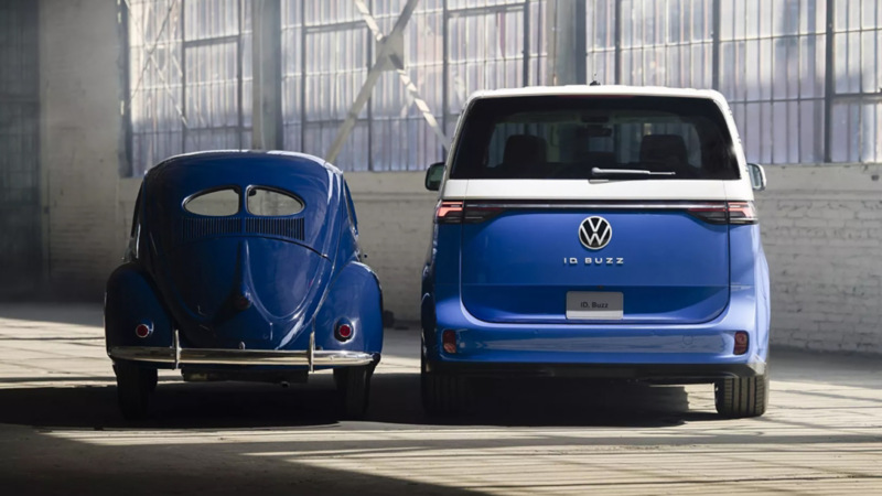 Blue VW beetle and blue ID.Buzz parked in a warehouse setting.