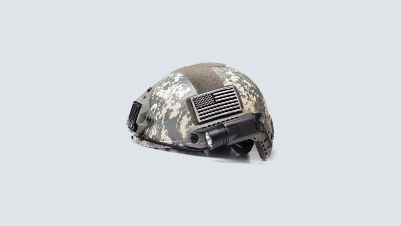 Casco de camuflaje con linterna y parche de bandera.