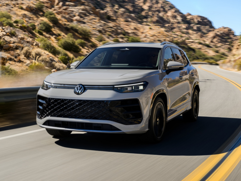 Front ¾  view of a Tiguan shown in Sandstone driving on a mountain road with rocks and shrubs making up the landscape.