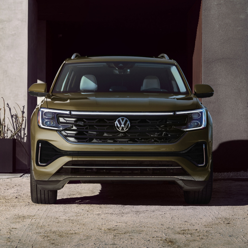 Front view of an Atlas in Avocado Green Metallic parked in a front of a building in a desert setting.