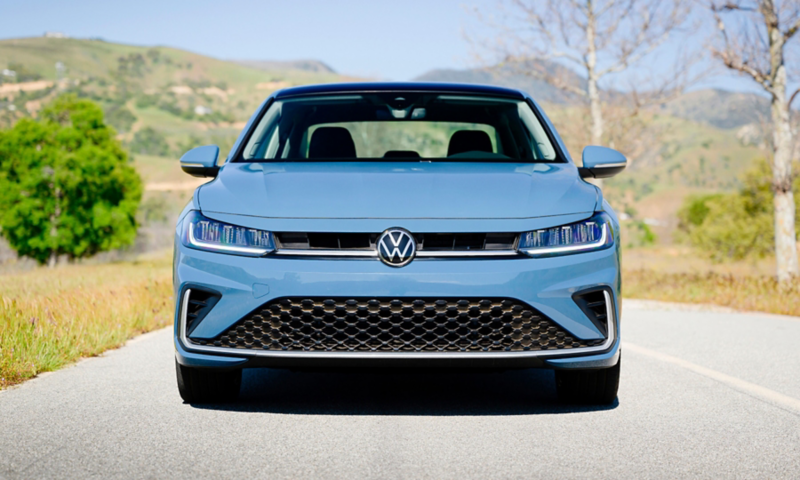 Head-on view of a Jetta shown in Monterey Blue Pearl parked on road with trees in the background.