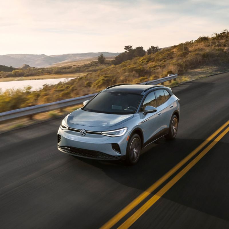 Front view of an ID.4 shown in Arctic Blue Metallic driving on a mountain road.
