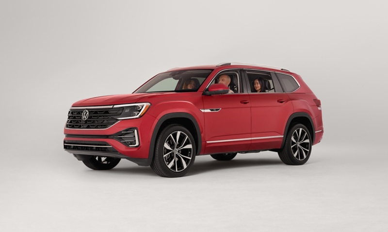 An Atlas shown in Aurora Red Metallic parked on a white studio backdrop with three people sitting in the vehicle.