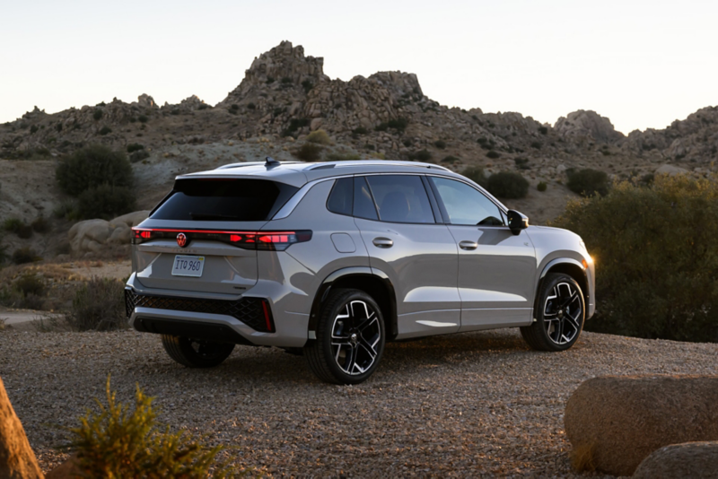 Rear view of a Tiguan shown in Sandstone parked in a mountainous terrain with rocks and shrubs making up the landscape.