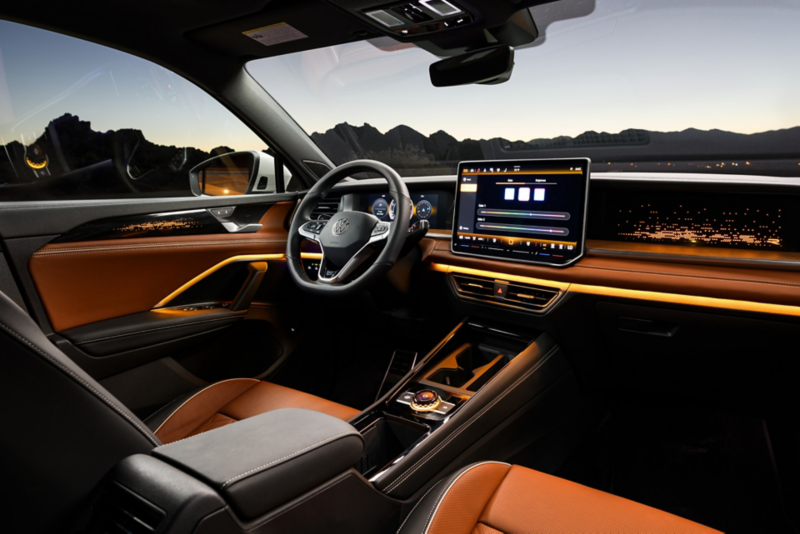 Interior view of a Tiguan shown in available Amber Brown leather looking from passenger's side out the windshield at dusk with mountains visible in the background.