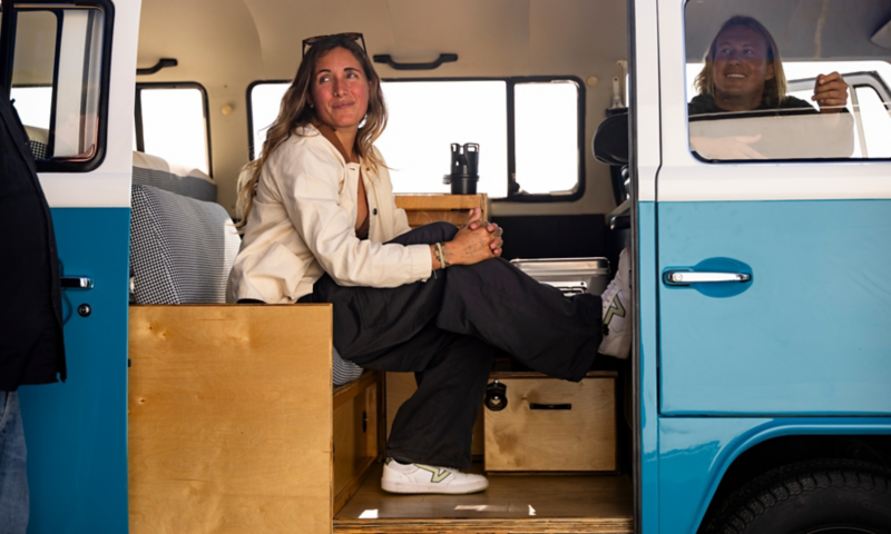 A woman sitting inside a vintage VW Bus with a man in the driver's seat.