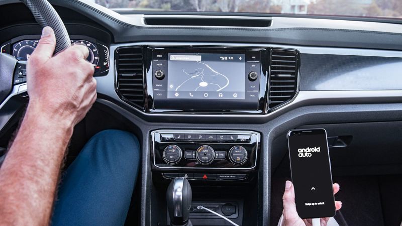 An interior dashboard view of the touchscreen navigation system shows a phone is plugged in and connected to Android Auto.