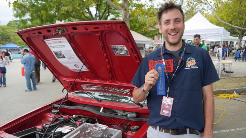 El profesor Ron Grosinger junto a un Volkswagen Cabriolet rojo de 1990 convertido de gas a eléctrico.