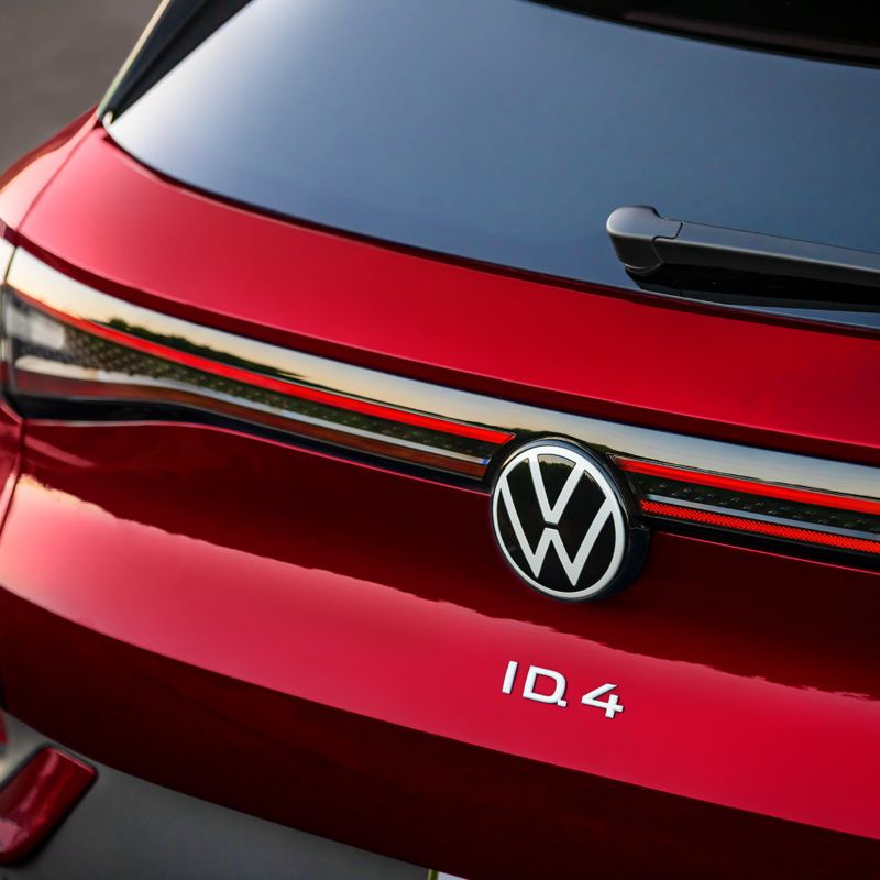 Primer plano de la parte trasera de un ID.4 de color Aurora Red Metallic con énfasis en las luces traseras, el emblema de VW y el logotipo del ID.4.