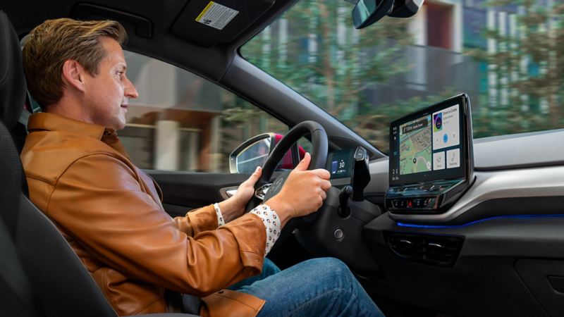 Interior view on a man in the driver seat an ID.4 SUV with his attention focused on the center console display at startup.