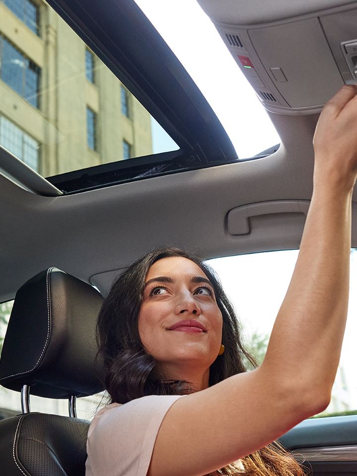 Available panoramic sunroof in use by a person seated in the driver seat.
