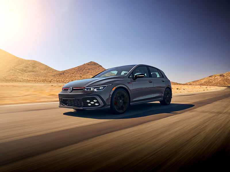 Golf GTI shown in Graphite Gray Metallic driving out of foothills into desert landscape.