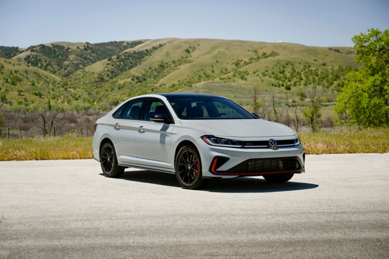 Front ¾ view of a Jetta GLI shown in Monument Gray with wooded hills in the background.