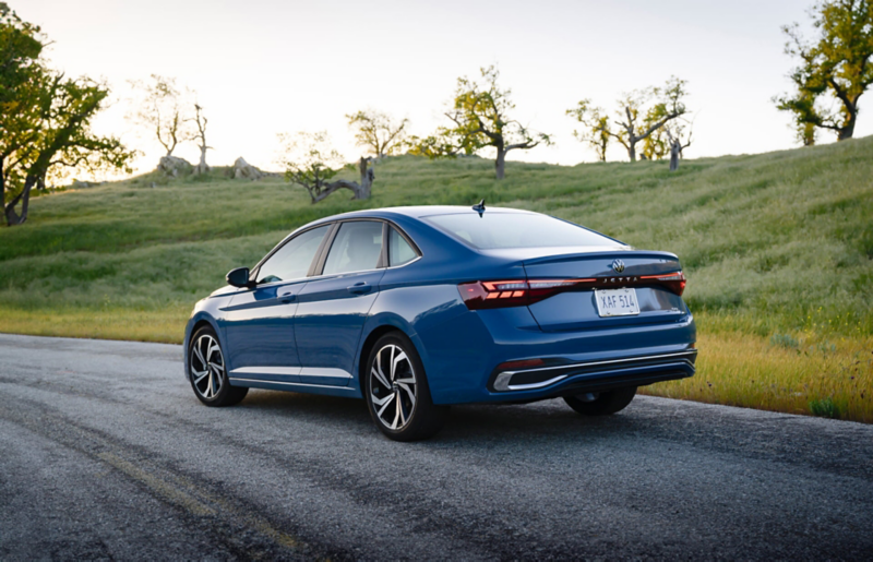 Rear view of a Jetta shown in Monterey Blue Pearl parked with trees in the background.