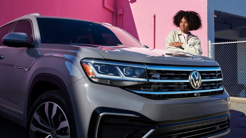 A woman proudly looks at her Atlas Cross Sport shown in Pure Gray.