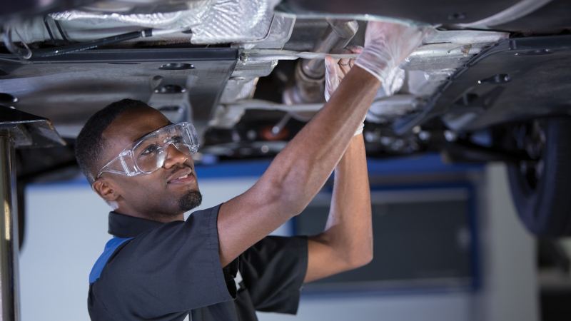 Service technician works on a car on a lift.