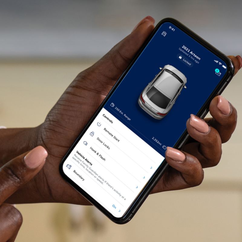 Close up shot of the hand of a person holding a phone displaying the MyVW app.