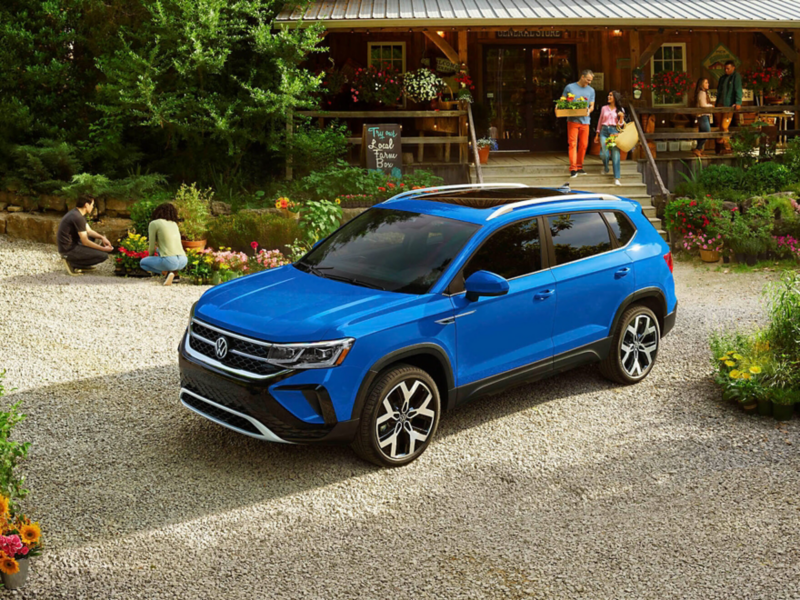 A Taos shown in Cornflower Blue is parked at a countryside market