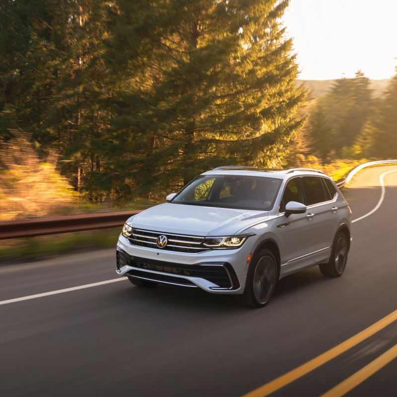 2023 VW Tiguan, shown in Opal White, driving on a winding road.