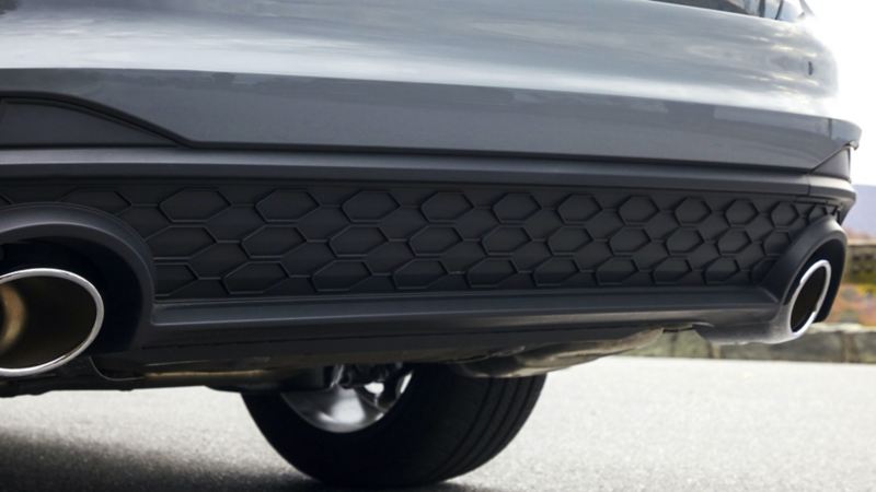 Closeup of the exhaust outlets and diffuser at the rear bumper of a VW Jetta GLI, shown in Pure Gray. Color adds an additional $395 to price of car.
