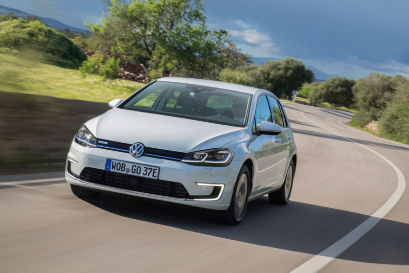 A man drives the 2013 Volkswagen e-Golf down the road showing front ¾ view of the vehicle.
