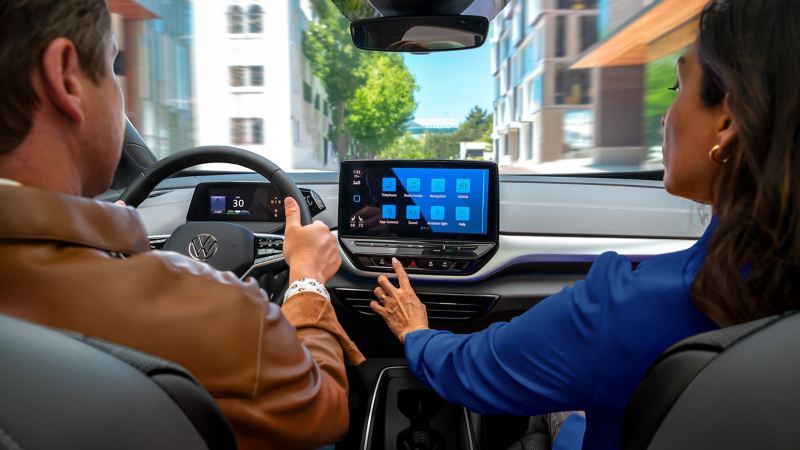 A close-up shot of an ID.4 dashboard, focusing on the passenger reaching out for the available 12” touchscreen display.