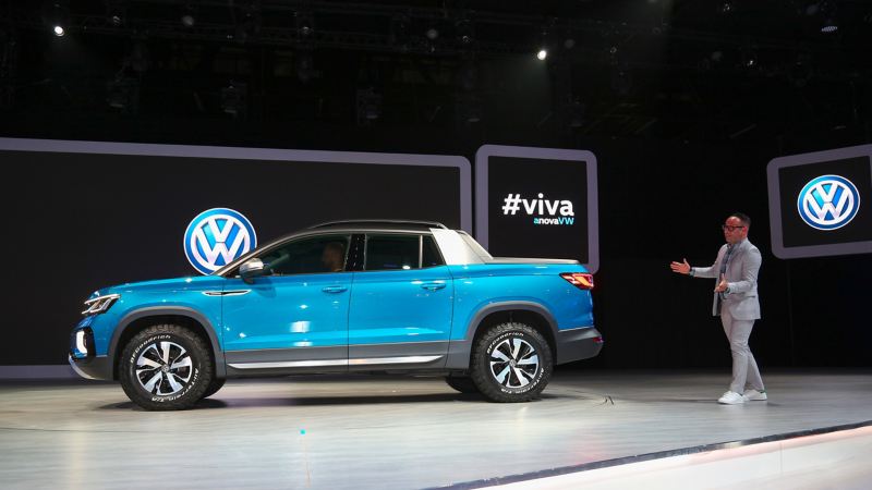 Presenter shows off Tarok concept pickup on auto show stage with vehicle in side profile.