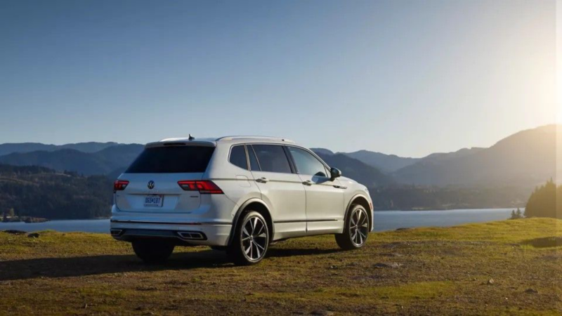 La renovada Tiguan 2022 de Volkswagen vista desde un ángulo trasero de tres cuartos junto a un lago.