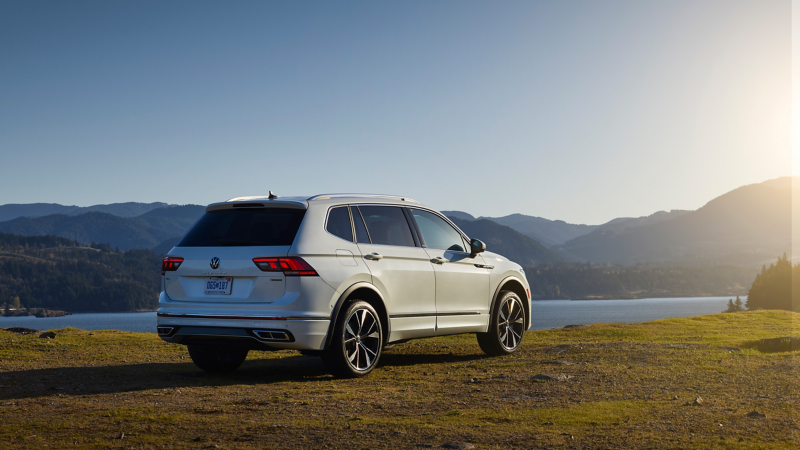 The refreshed 2022 Volkswagen Tiguan shown in rear three-quarter view by a lake.